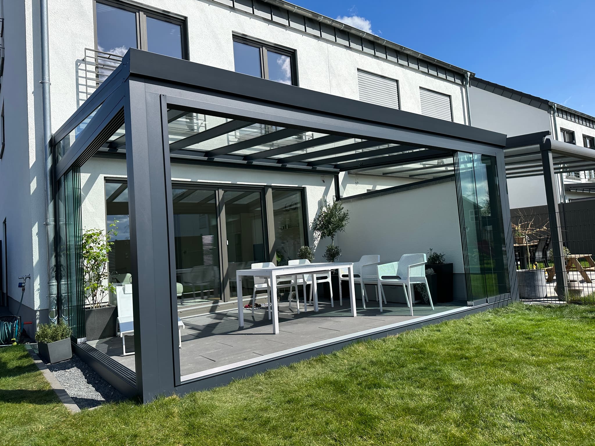 Aluminium-Terrassenüberdachung neben einer Holz-Pergola im Garten — Direktvergleich der Materialien